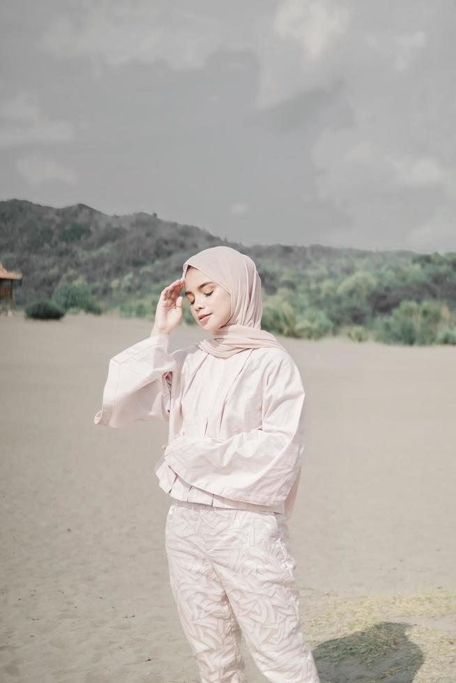 Beautiful islamic female model wearing hijab fashion, a modern wedding dress for muslim woman walks along the sand and the sea. A asian girl model using hijab having fun at the beach. Photo prewedding