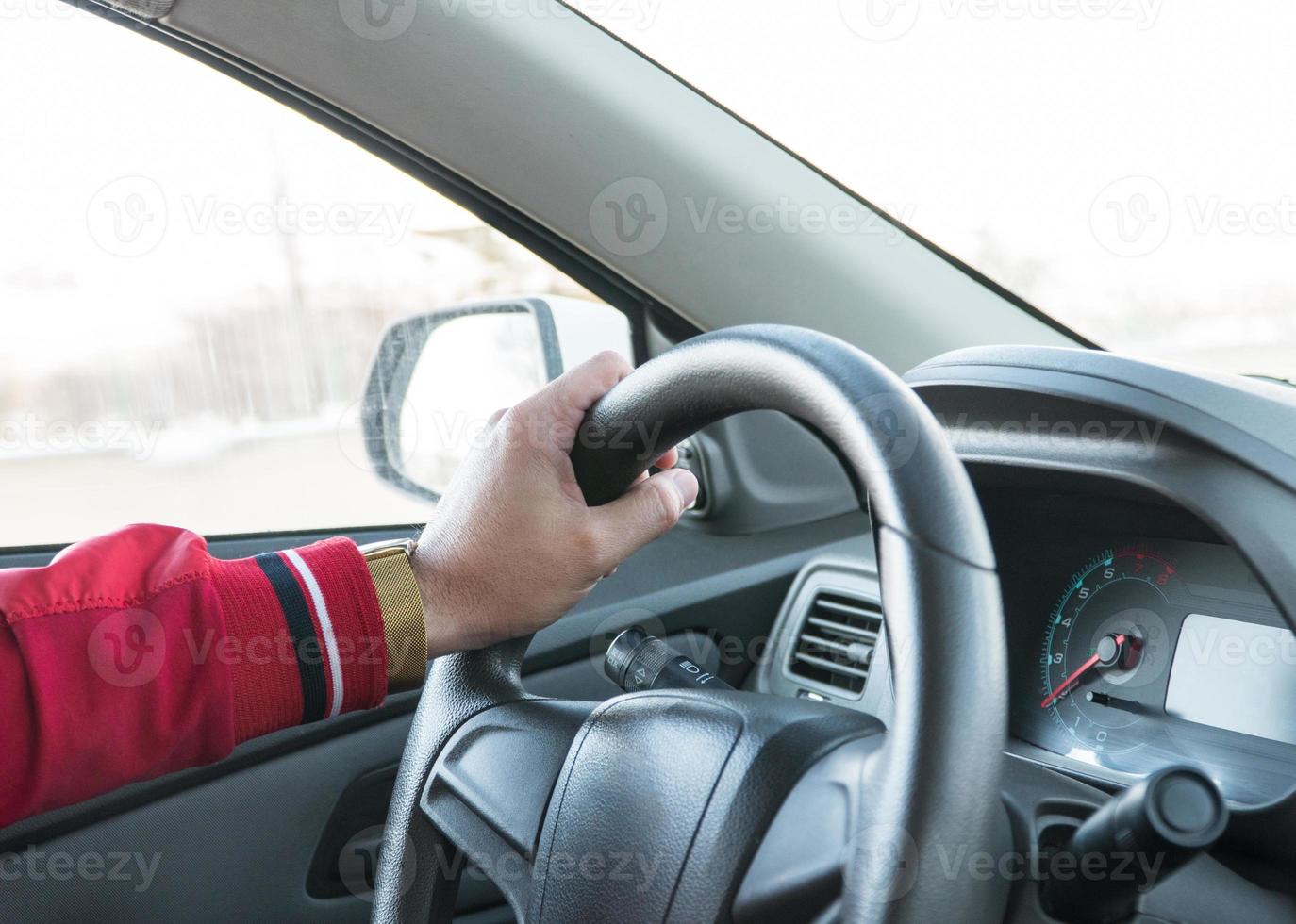 men's hand with a watch on the steering wheel of a modern car photo