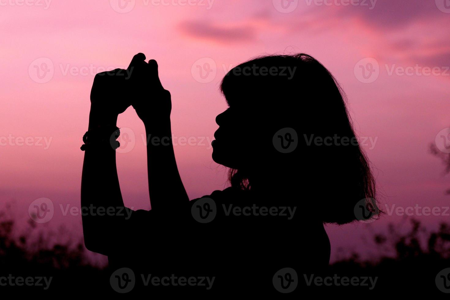 silueta mediana de una mujer o una mujer de pie con el fondo de la puesta de sol en el cielo a la hora de la puesta del sol. foto
