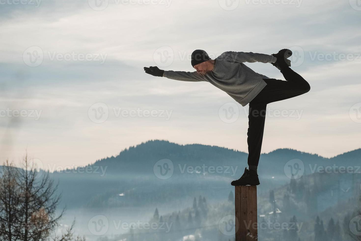 Man doing yoga exercises in front of amazing sunset on the winter mountains. Copy, empty space for text photo