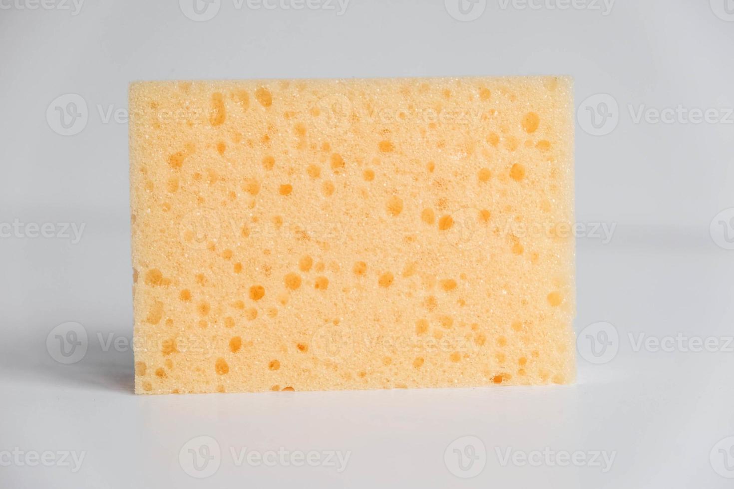 esponja porosa amarilla sobre un fondo blanco foto