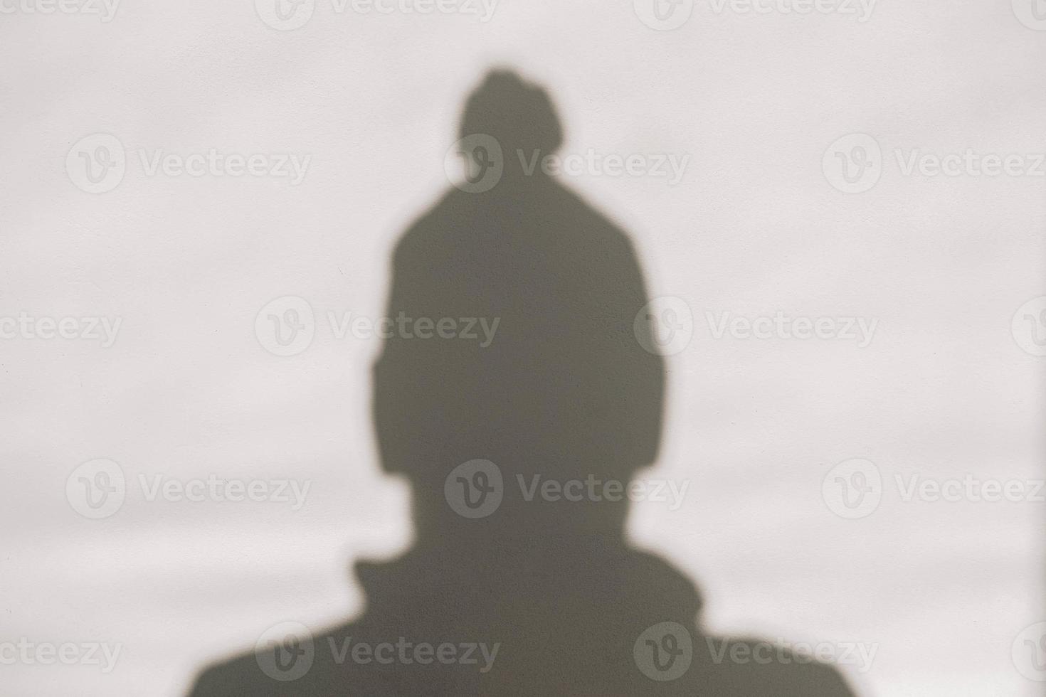 Shadow and silhouette of a man in a winter hat on a white wall photo