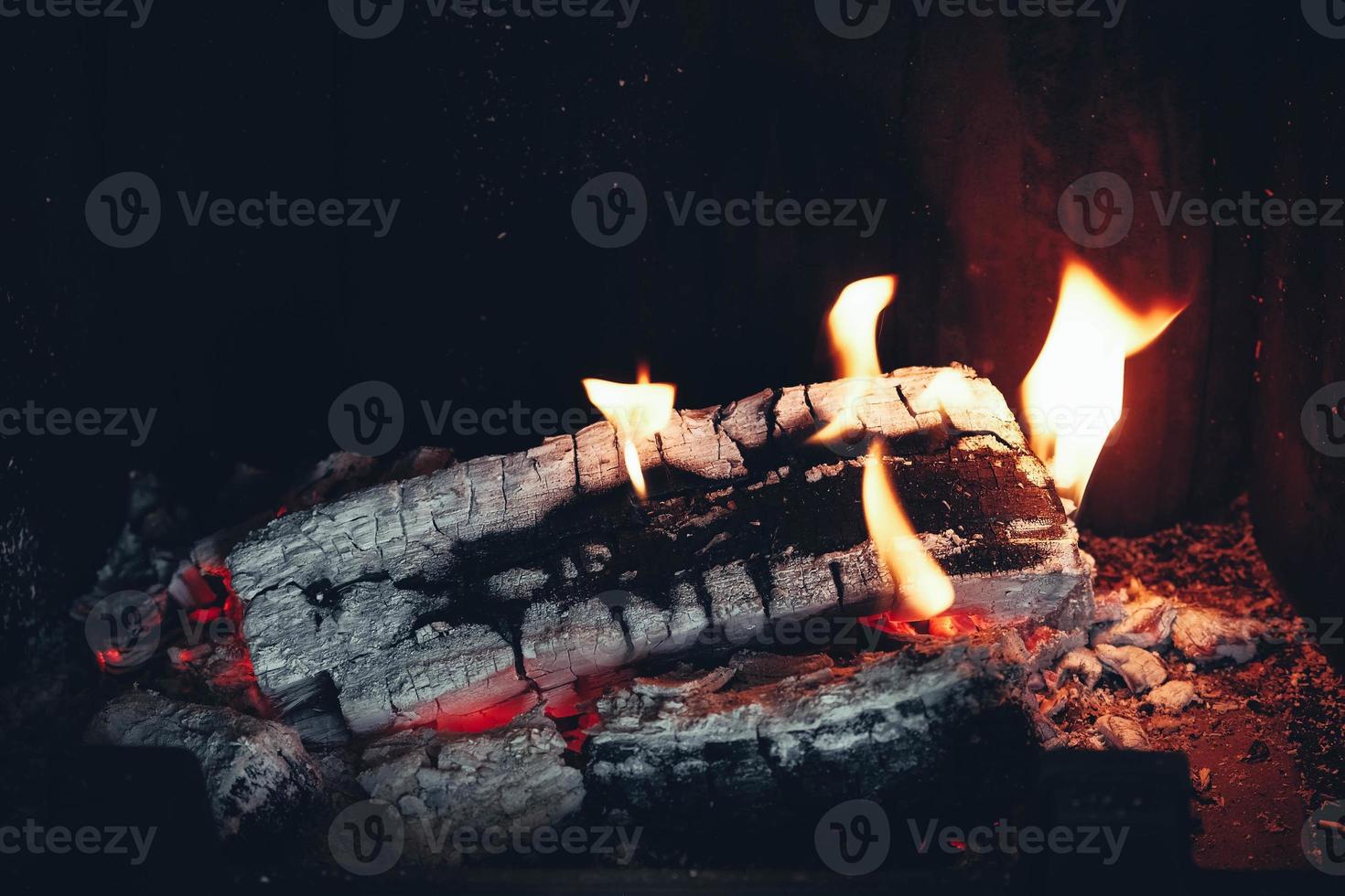 Firewood burning in the fireplace. Wood logs fire glowing in the dark. Copy, empty space for text photo