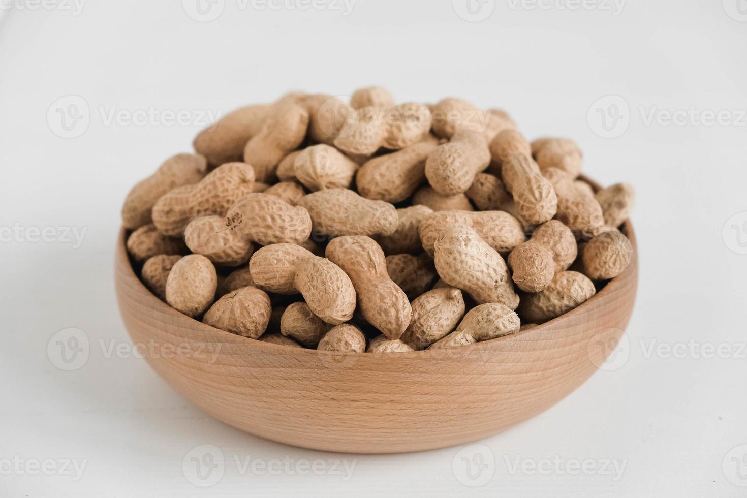 Dry peanuts in shell in a wooden bowl on a white background photo