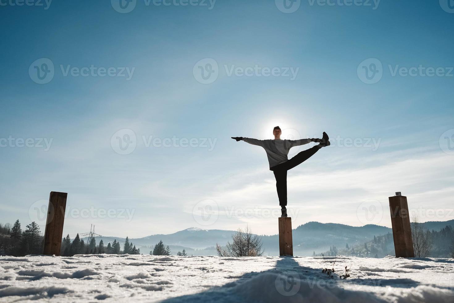 Silhouette of a man doing yoga exercises in front of amazing sunset on the winter mountains. Copy, empty space for text photo