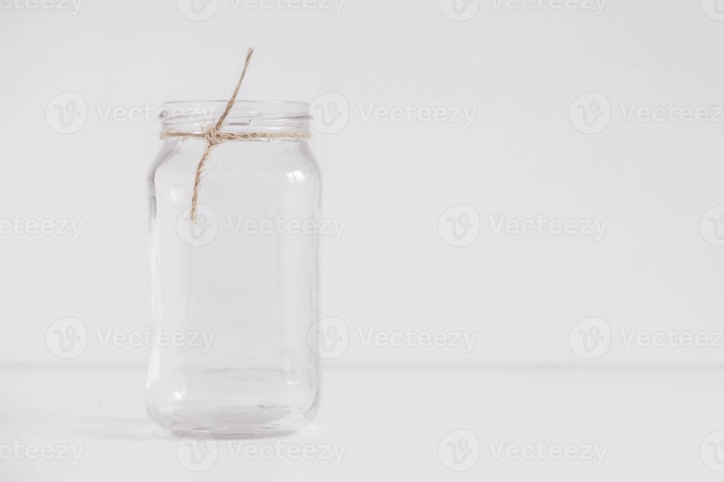 Glass transparent jar on a white table and wall background. Copy, empty space for text photo