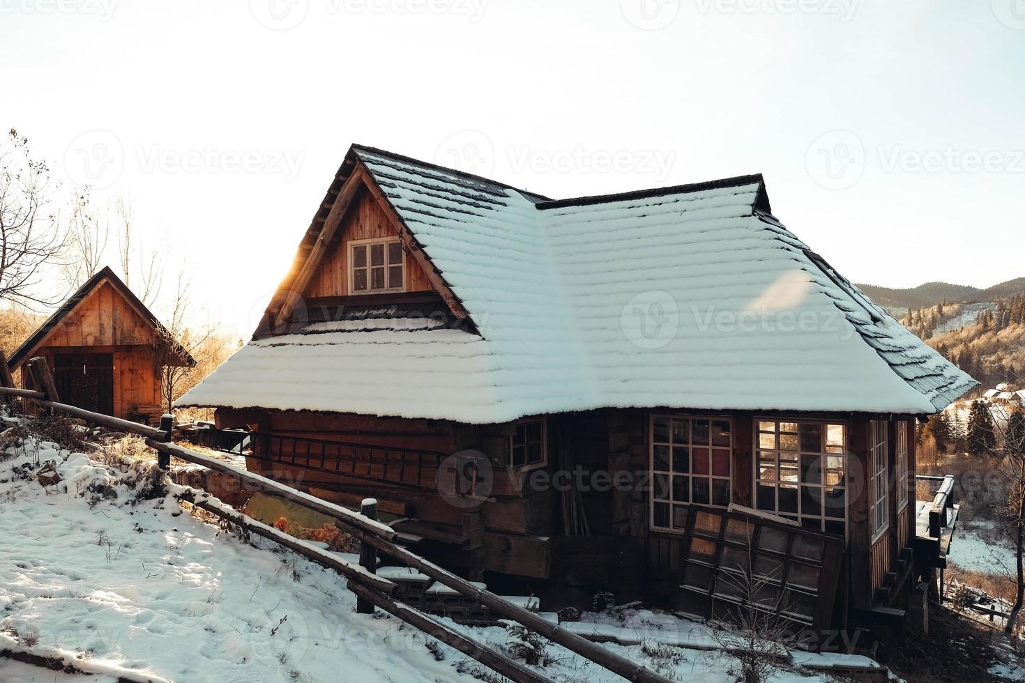 Wooden house at sunset on a background of snowy mountains. Winter landscape in the Carpathians. Ukraine, Europe. Copy, empty space for text photo