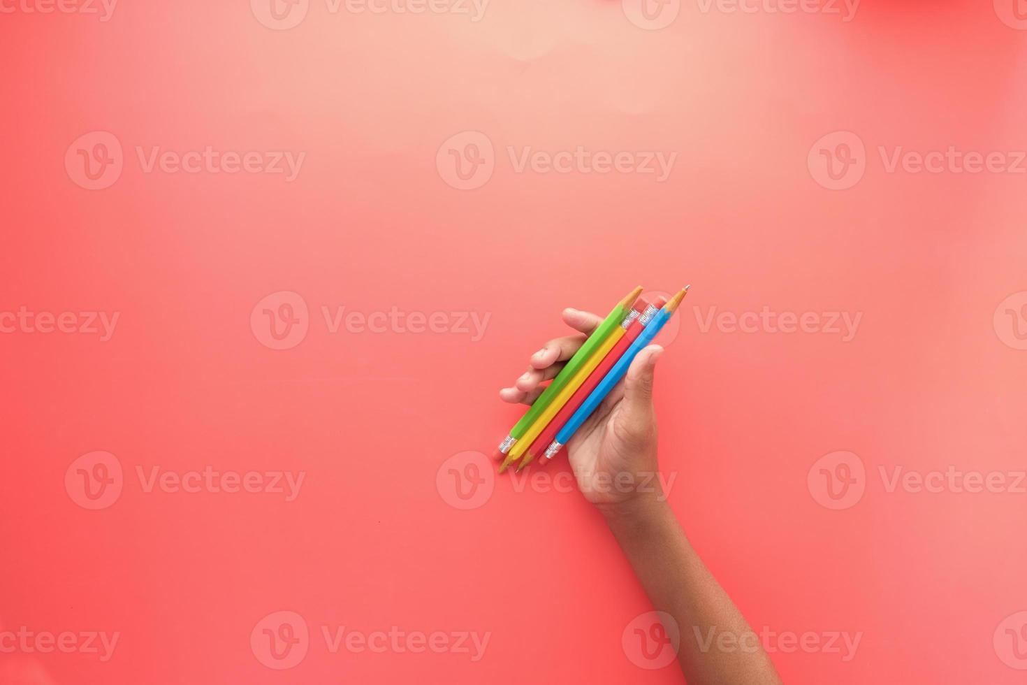 child girl holding many color pencils on red background photo