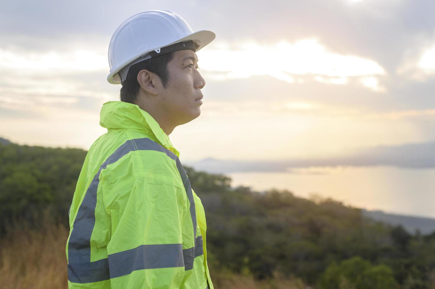 un ingeniero le está poniendo un casco protector en la cabeza al atardecer. foto