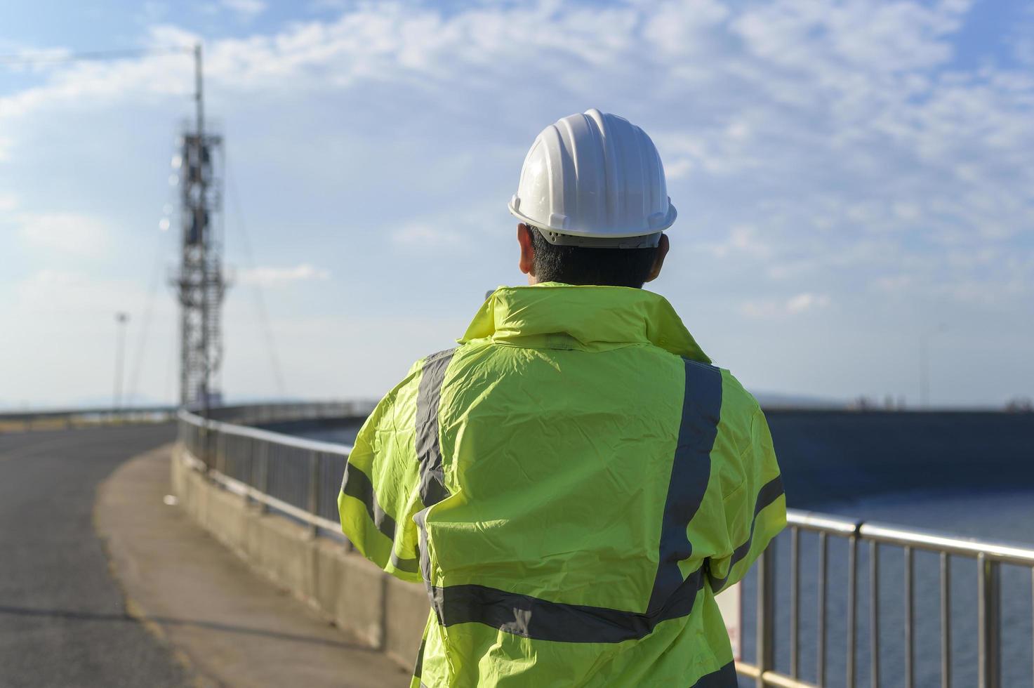 a man engineer is wearing a protective helmet on her head, using tablet Analytics engineering data. photo