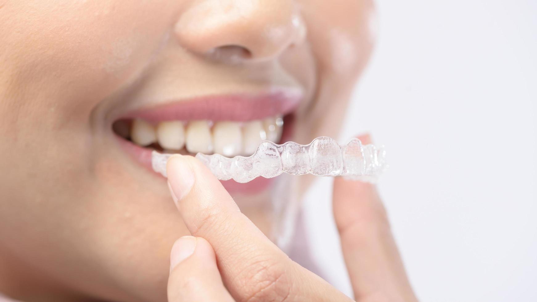 joven mujer sonriente sosteniendo llaves invisalign sobre estudio de fondo blanco, cuidado de la salud dental y concepto de ortodoncia. foto