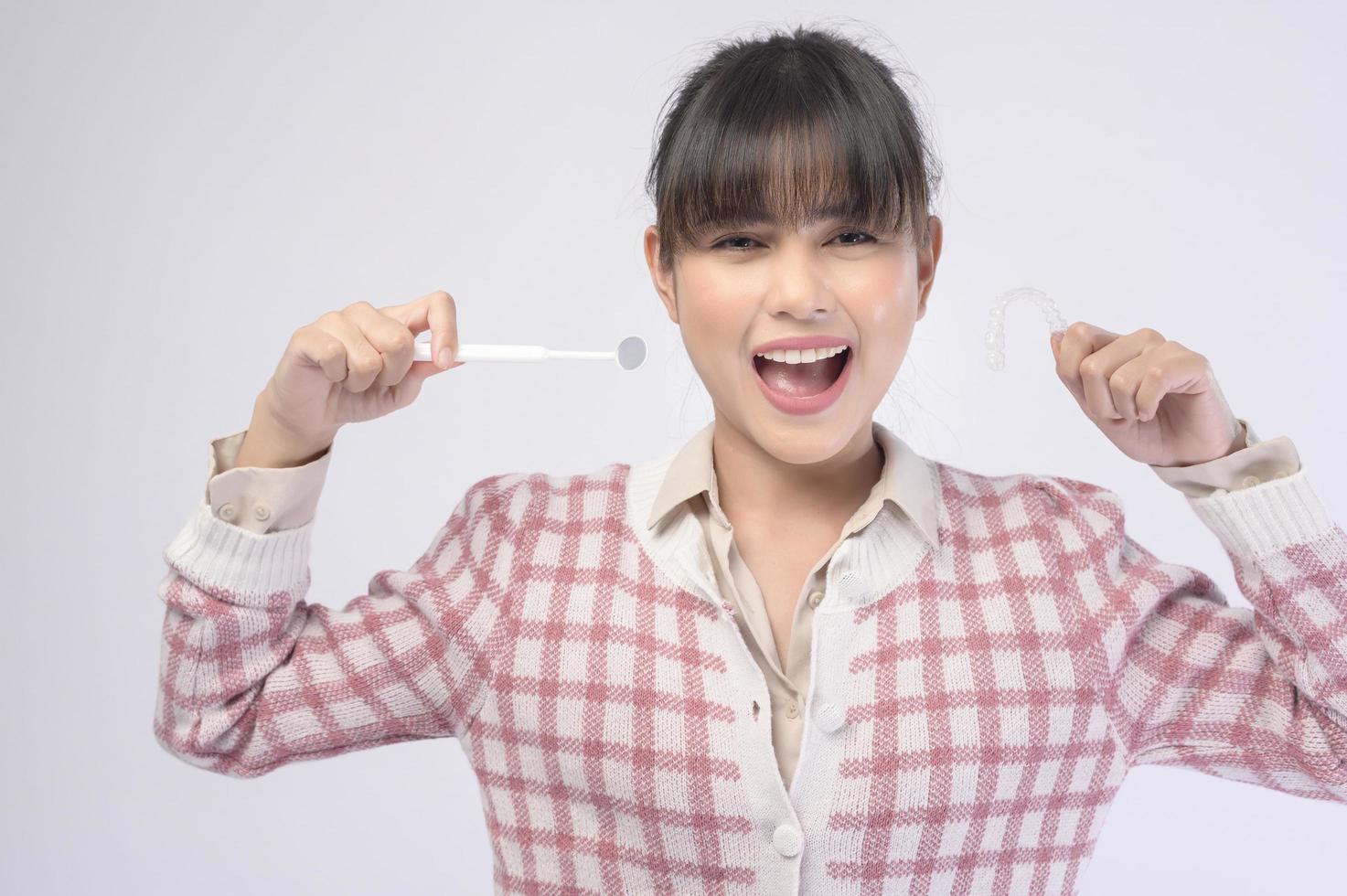 Young smiling woman holding invisalign braces over white background studio, dental healthcare and Orthodontic concept. photo