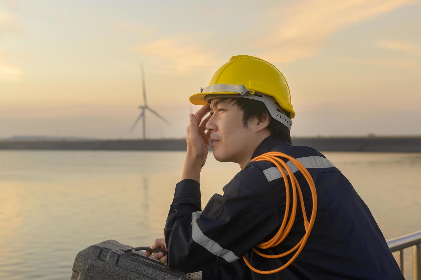 A male engineer wearing a protective helmet at sunset. photo