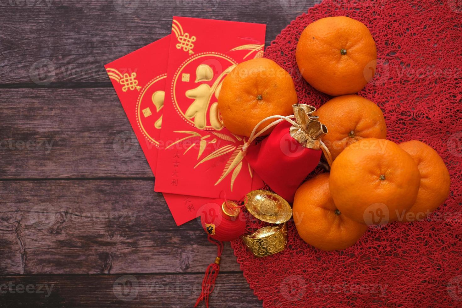 Chinese New Year feen background. Chinese character fu fesstival concept. Mandarin oranges, red envelopes, gold ingots and tea pot on red cloth with old wood which stands for luck photo