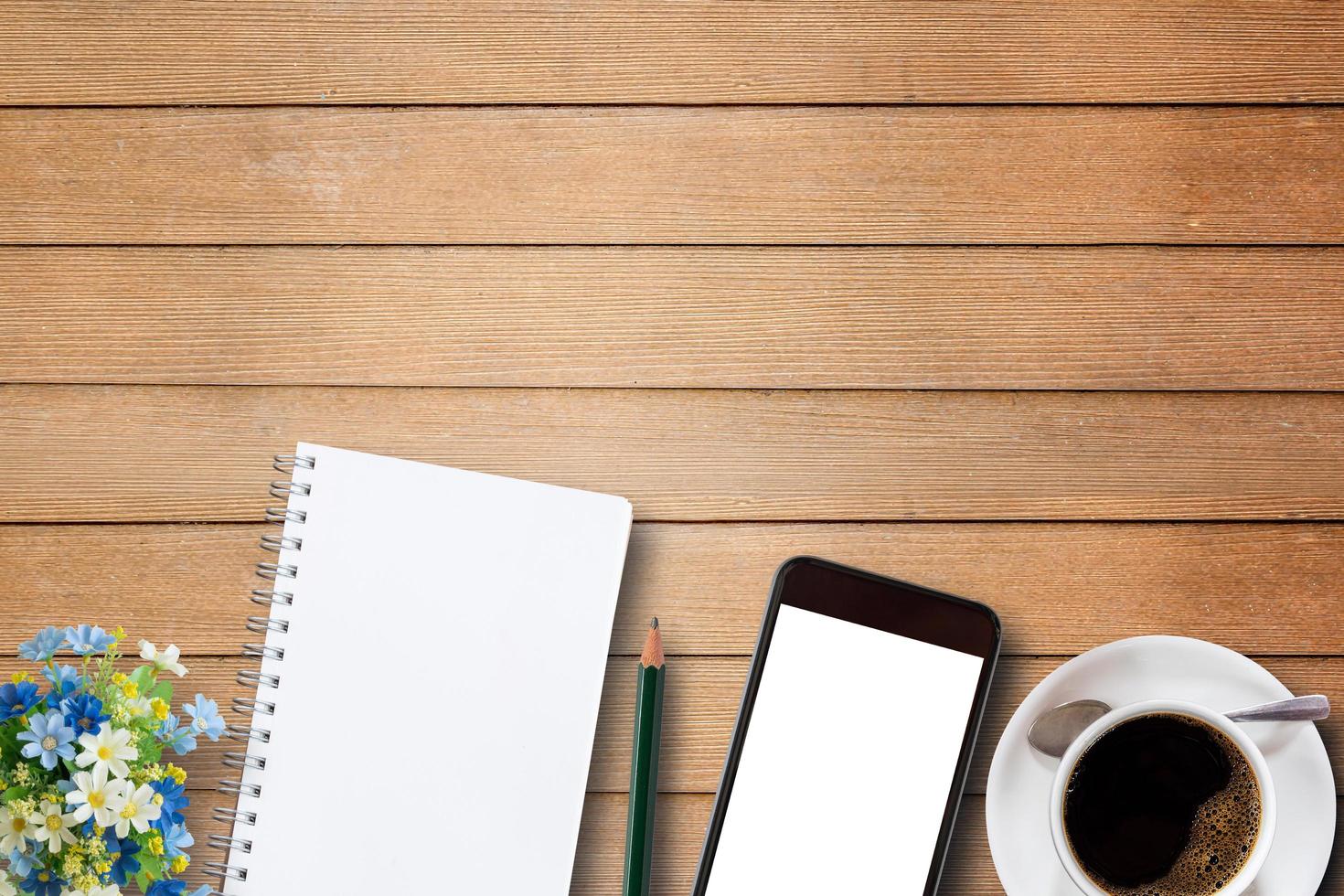 cuaderno en blanco, teléfono inteligente y taza de café en madera foto