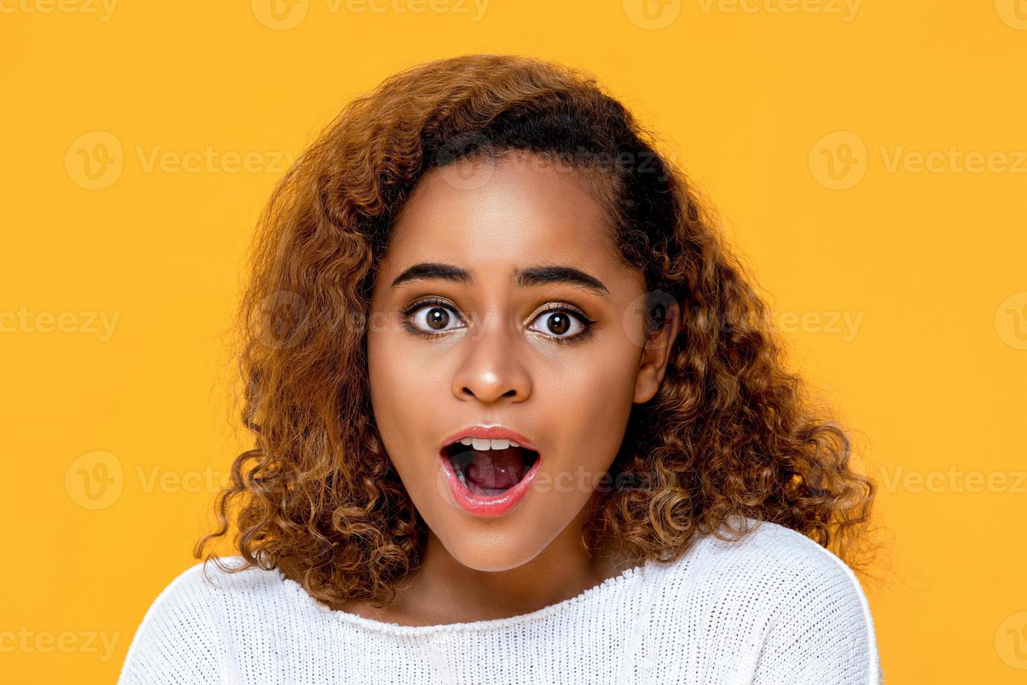 Surprised mixed African woman gasping isolated on yellow background photo