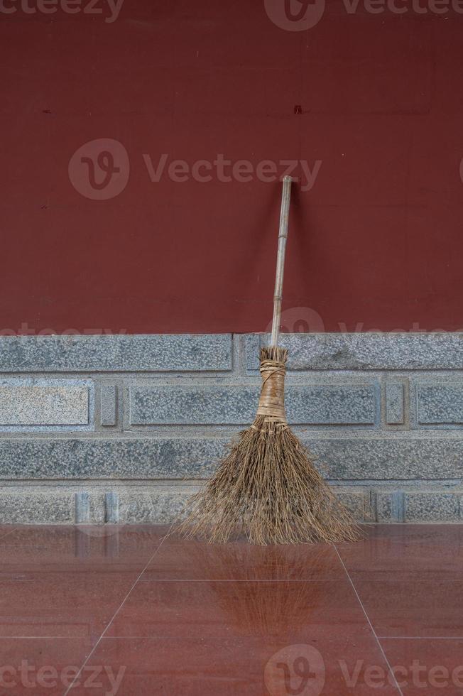 A broom by the red corner wall photo