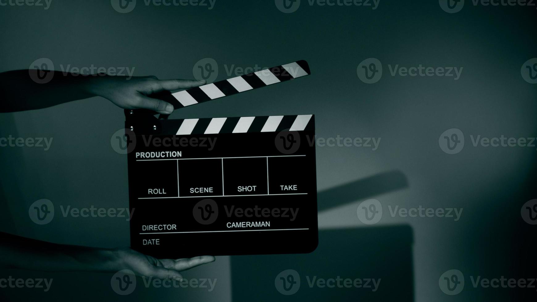 Hand holds empty film making clapperboard on color background in studio photo