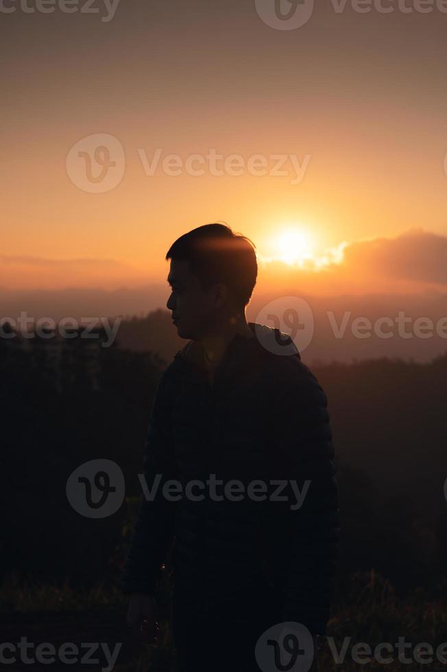 hombre viajero parado en el pico de la montaña al atardecer foto