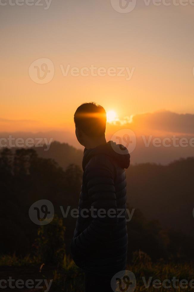 Traveler man standing on mountain peak in the sunset photo