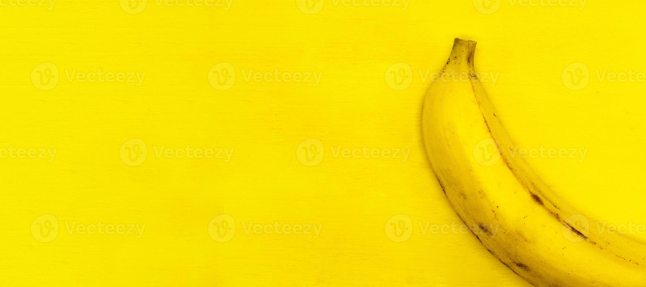 Ripe banana isolated on a yellow background close up with a blank space for your text photo