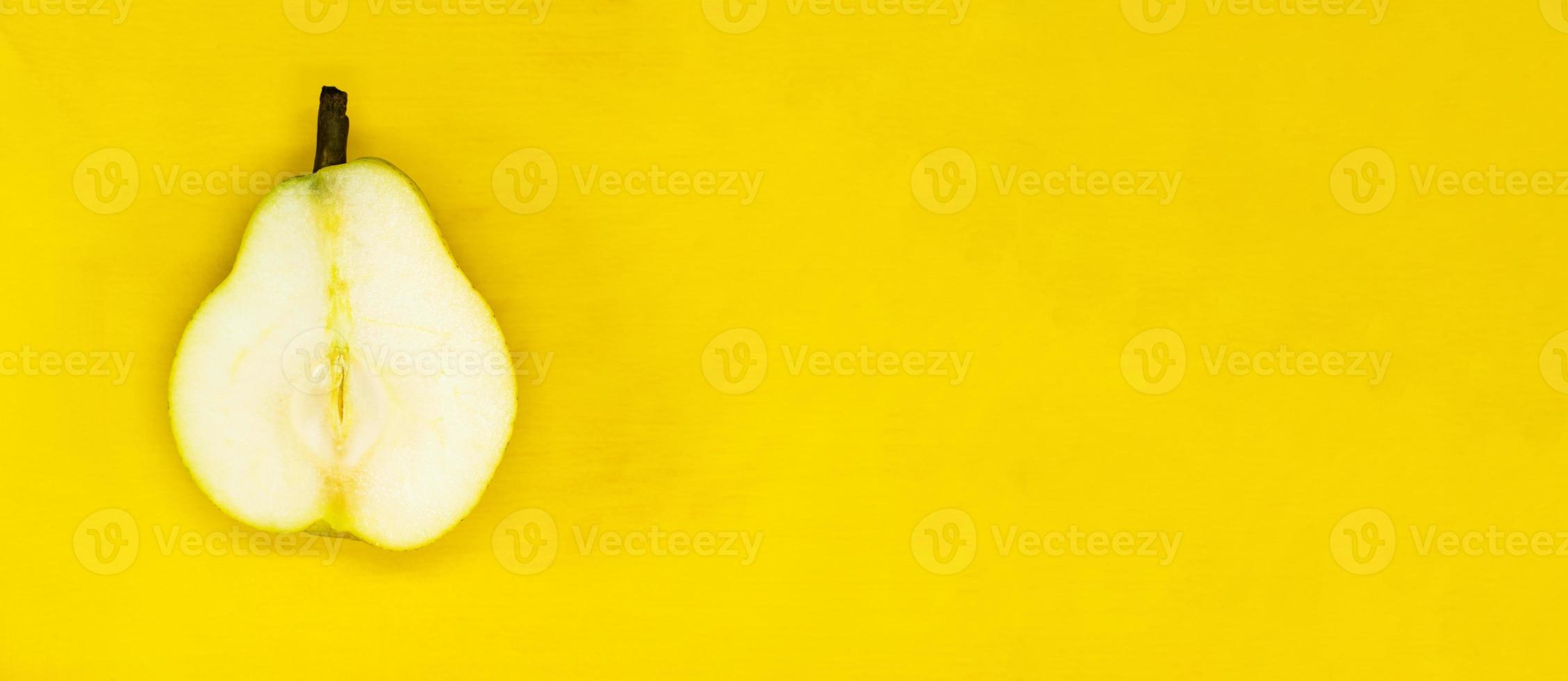 juicy pear cut isolated on a yellow background close up with a blank space for your text photo