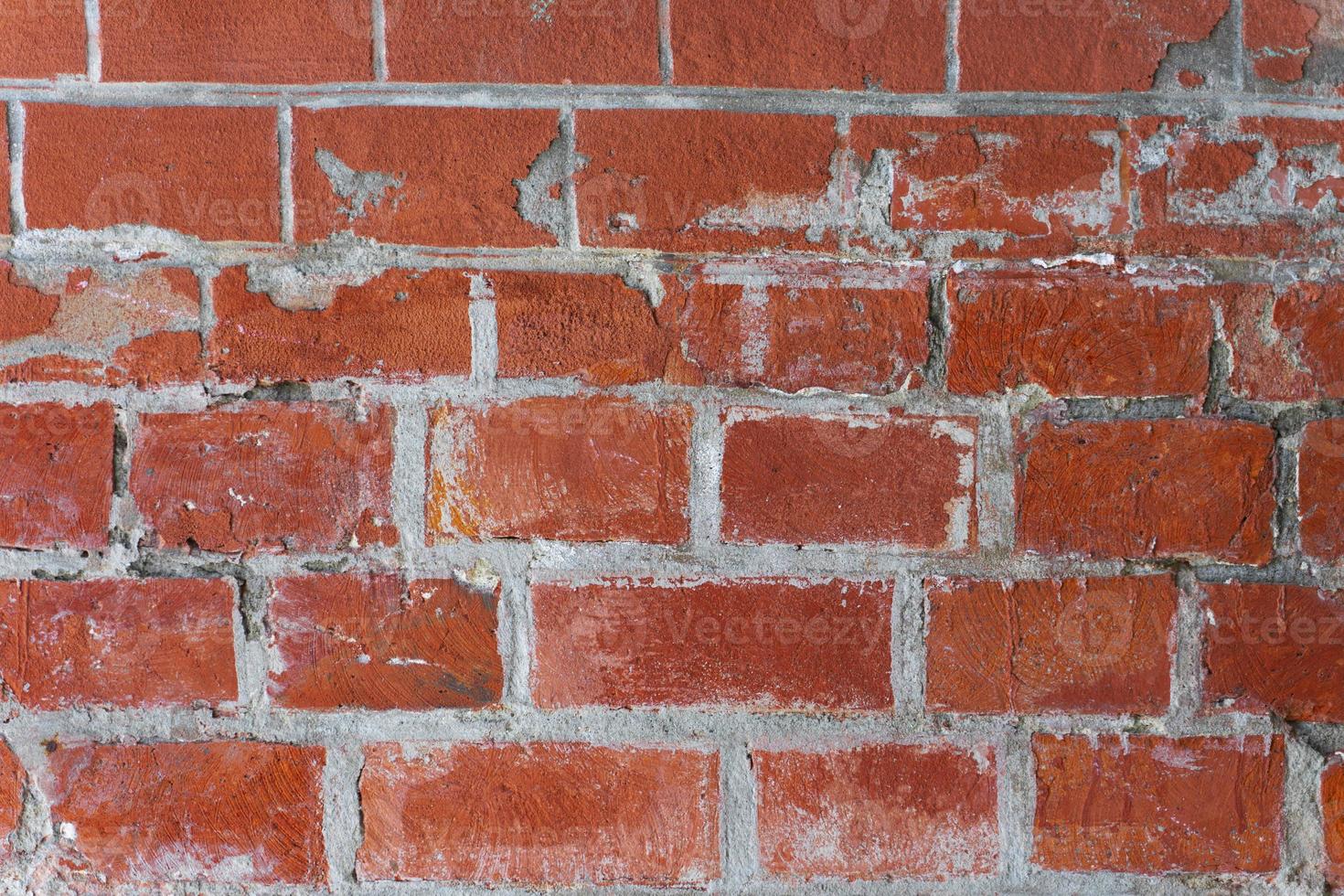 An old ragged imitation of a brick wall. Red brick, white grout. photo