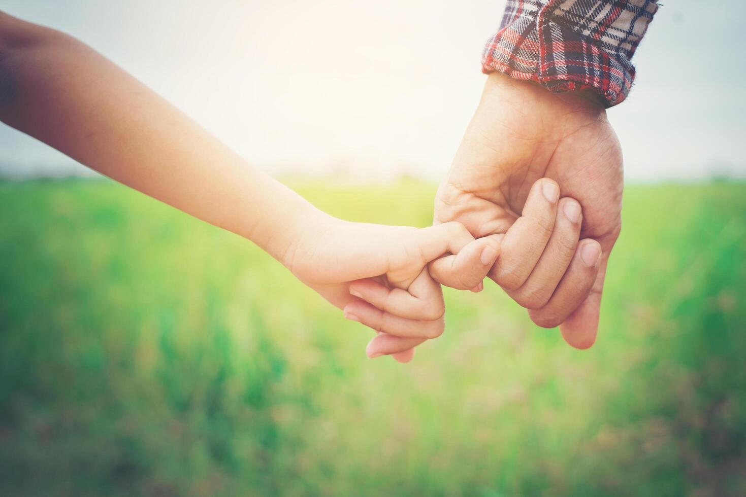 primer plano del padre sosteniendo la mano de su hija, tan dulce, tiempo en familia. foto