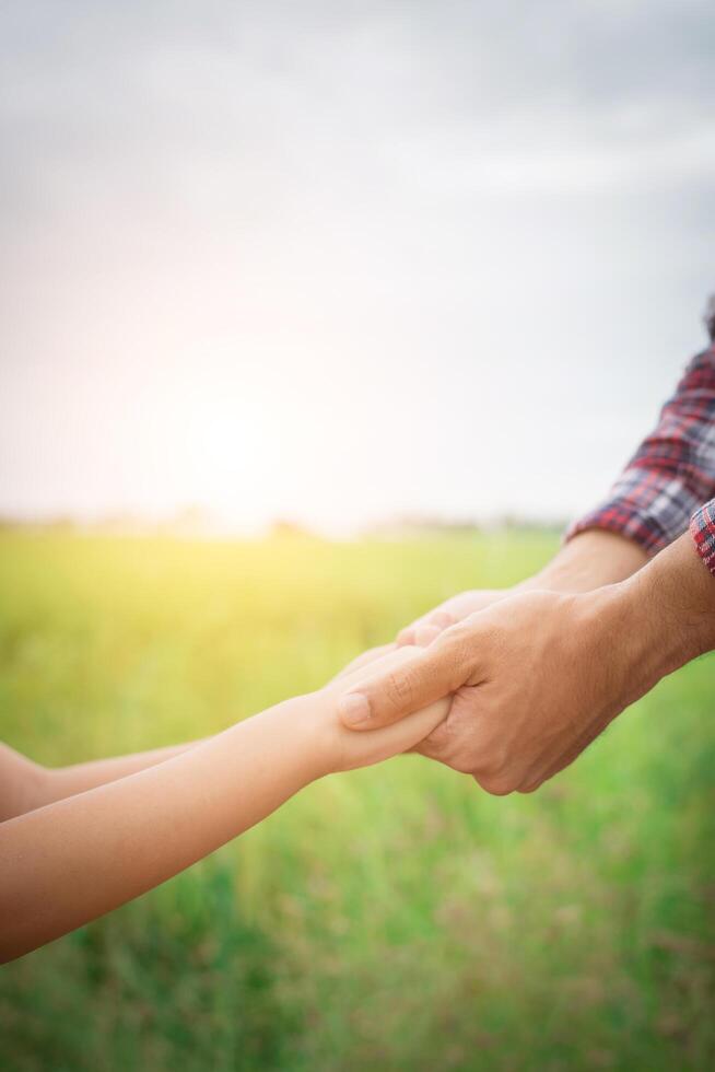 primer plano del padre sosteniendo la mano de su hija, tan dulce, tiempo en familia. foto