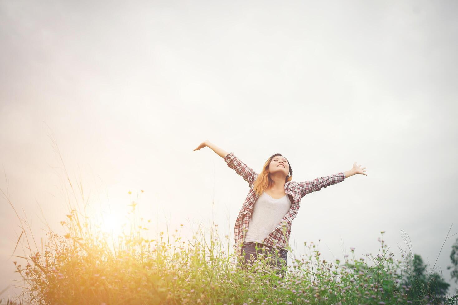 mujer joven hermosa hipster en un campo de flores al atardecer. libertad disfrutando con la naturaleza. foto