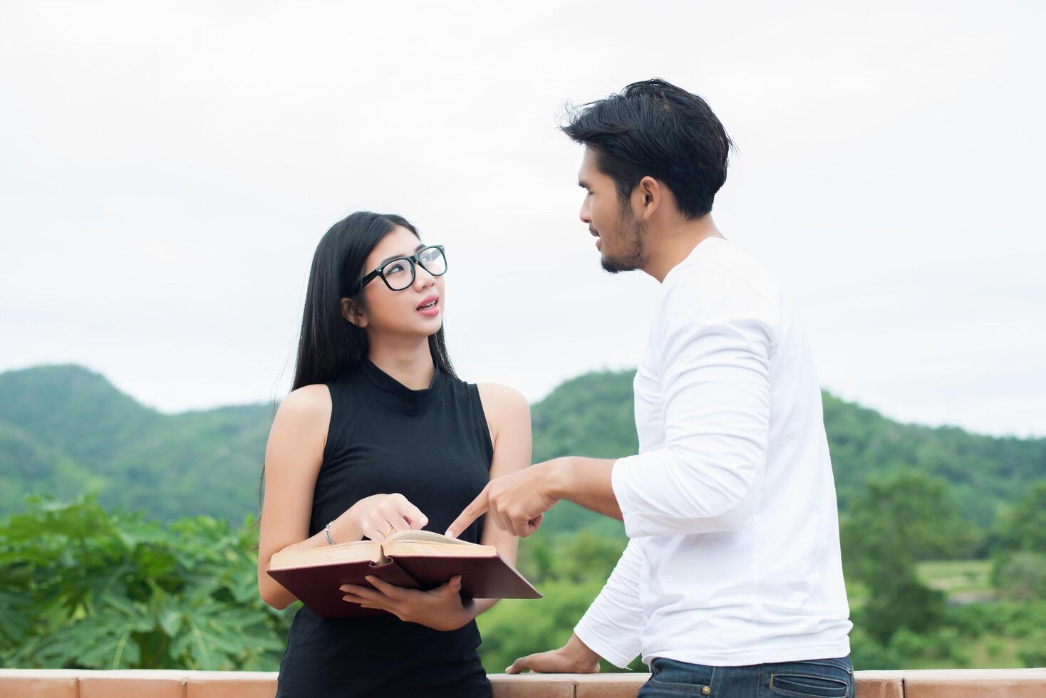 Young hipster couple enjoying a good read together while relaxing outdoors. photo