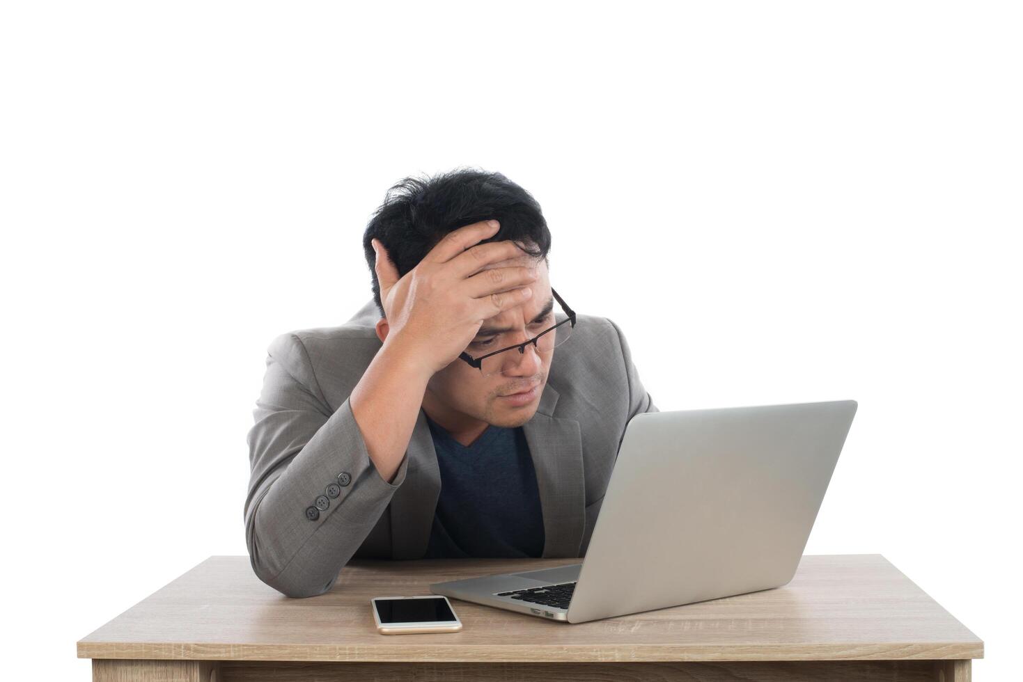 Stressed businessman work  with laptop sitting at table isolated on white background. photo