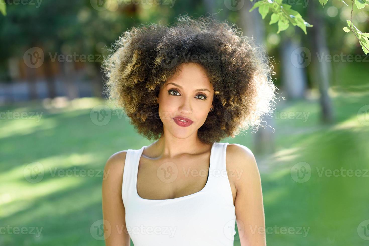 Young black woman with afro hairstyle smiling in urban park photo