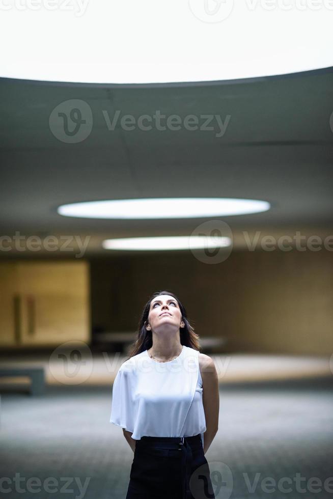 hermosa mujer morena, modelo de moda, posando en un edificio moderno. foto