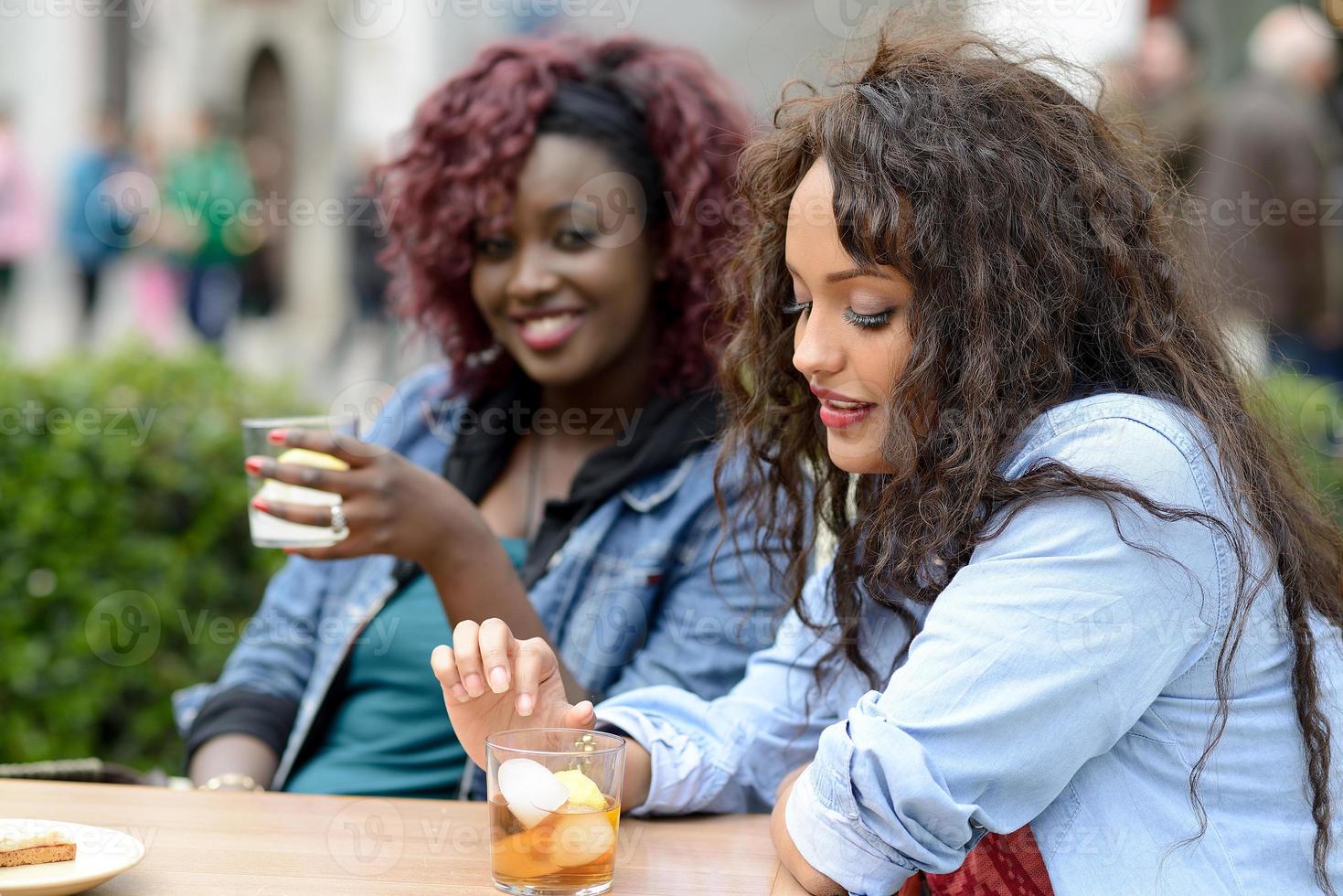 retrato de dos mujeres tomando una copa en un bar. fondo urbano foto