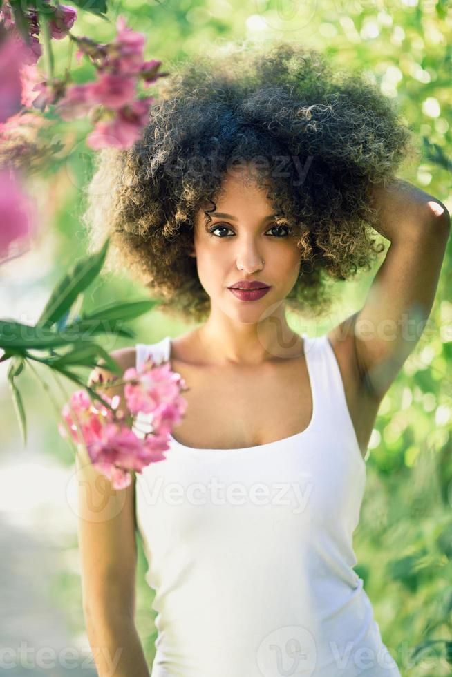 Young black woman with afro hairstyle smiling in urban park photo