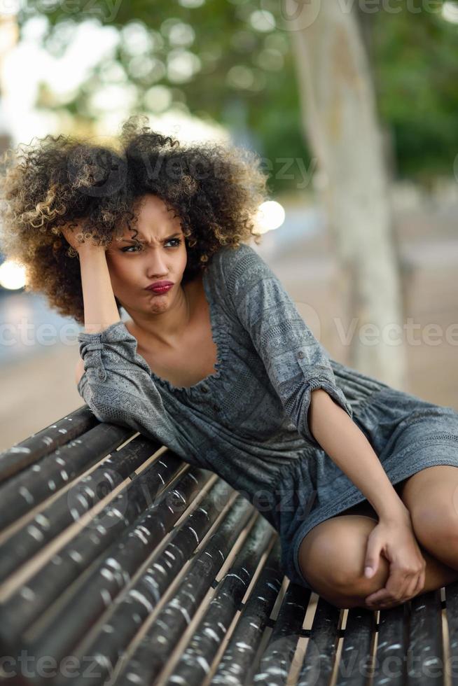 Young black woman with afro hairstyle smiling in urban background photo