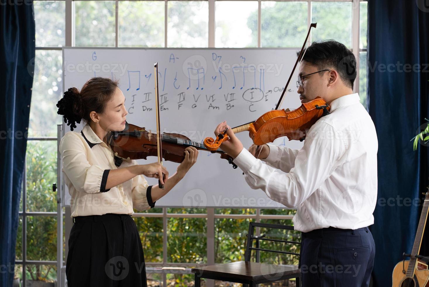 student learning how to play violin with teacher in classroom photo