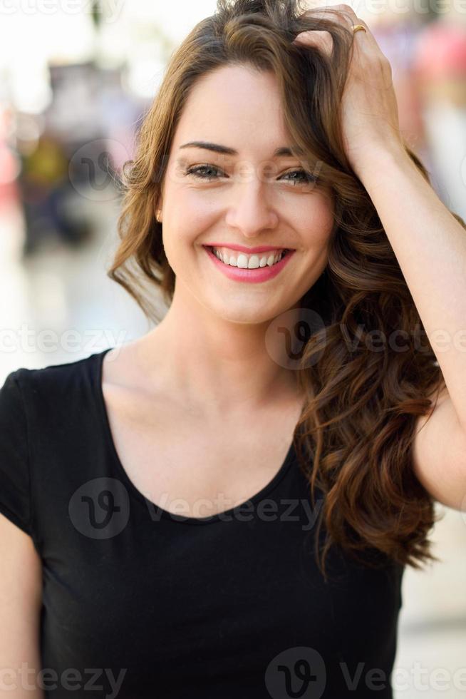 Beautiful young woman with blue eyes smiling in urban background photo