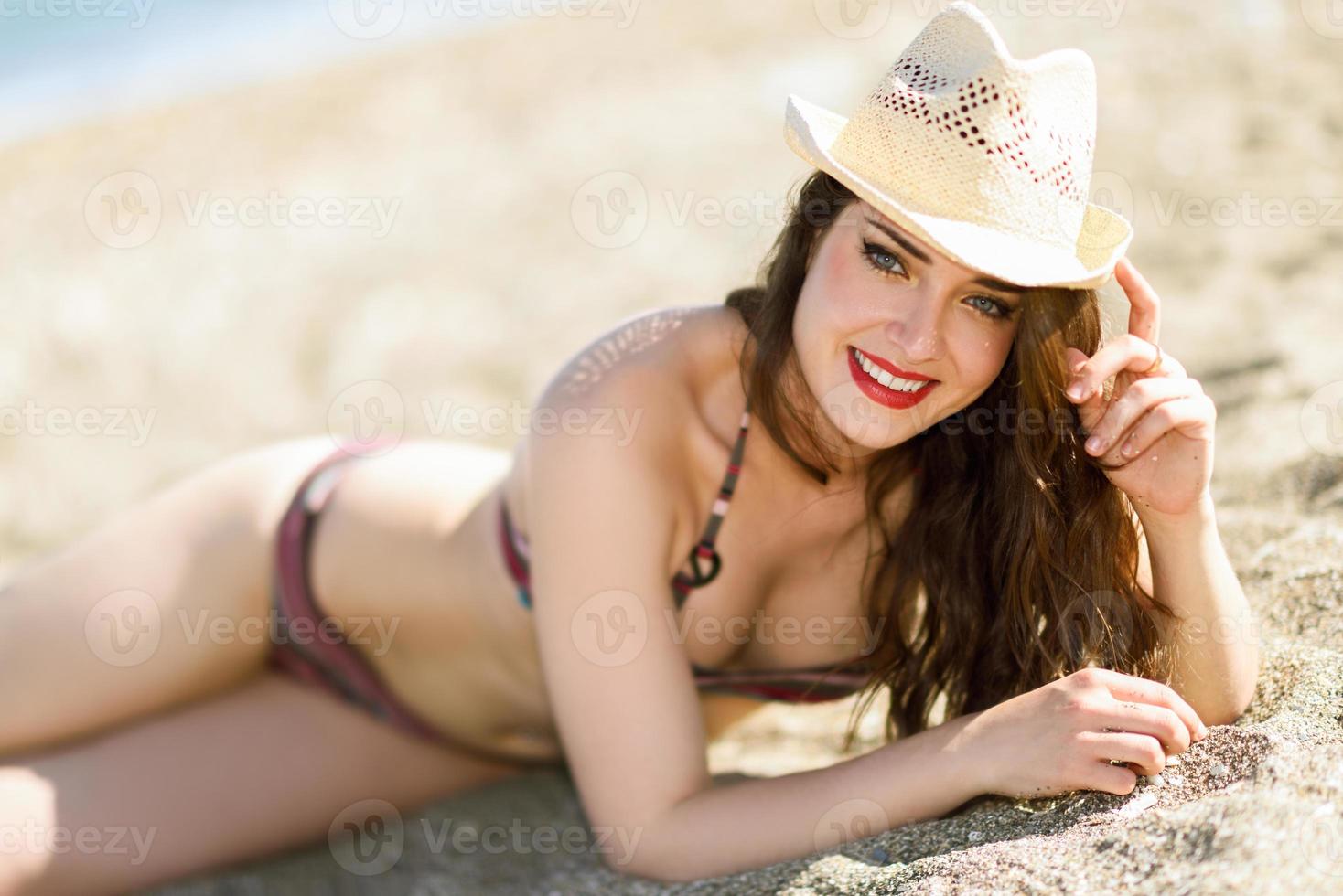 Young smiling woman lying in the sand in the beach photo