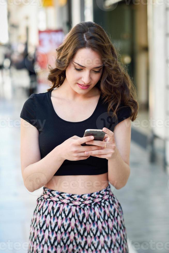 Young woman texting with a smartphone in urban background photo
