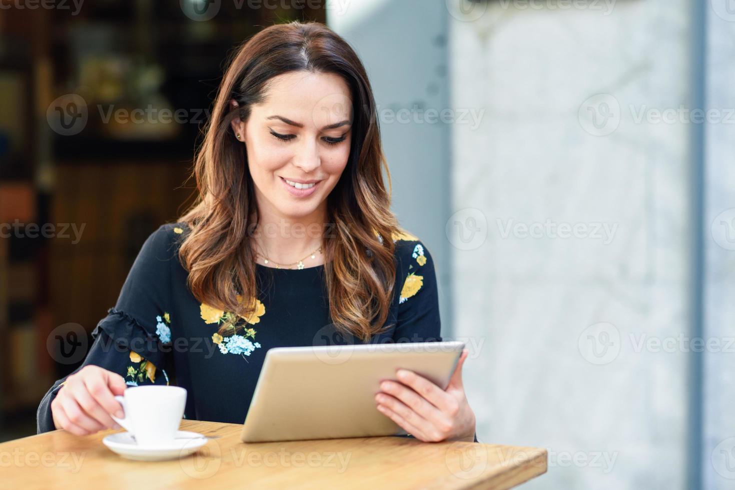 mujer de mediana edad que usa una tableta en un descanso para tomar café en un café bar urbano. foto