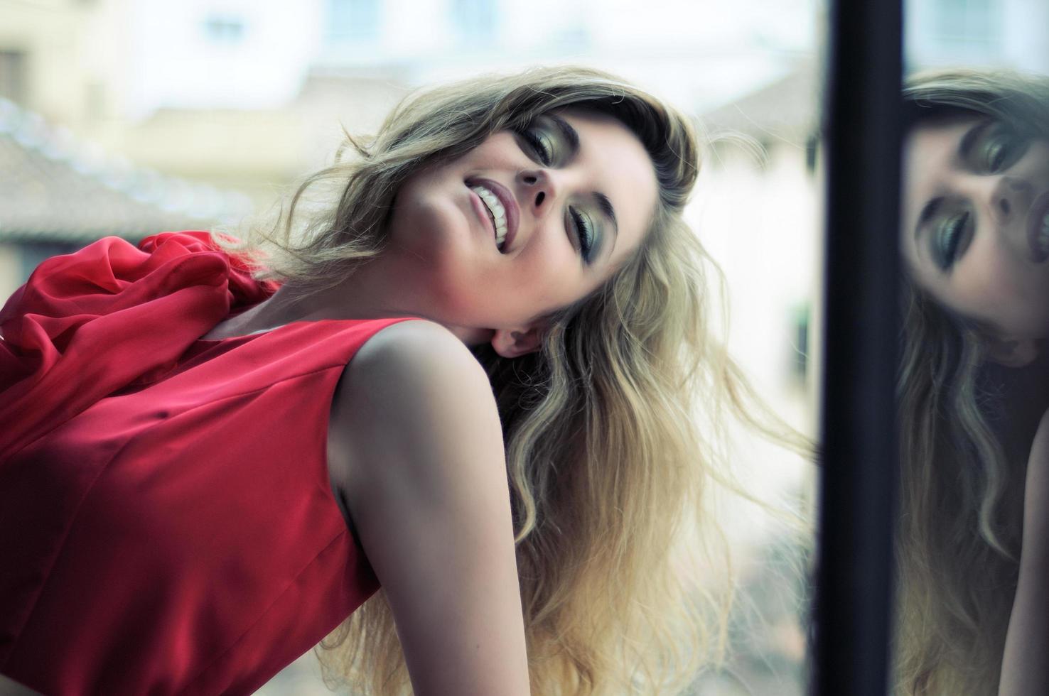 Beautiful blonde woman in window wearing a red dress photo