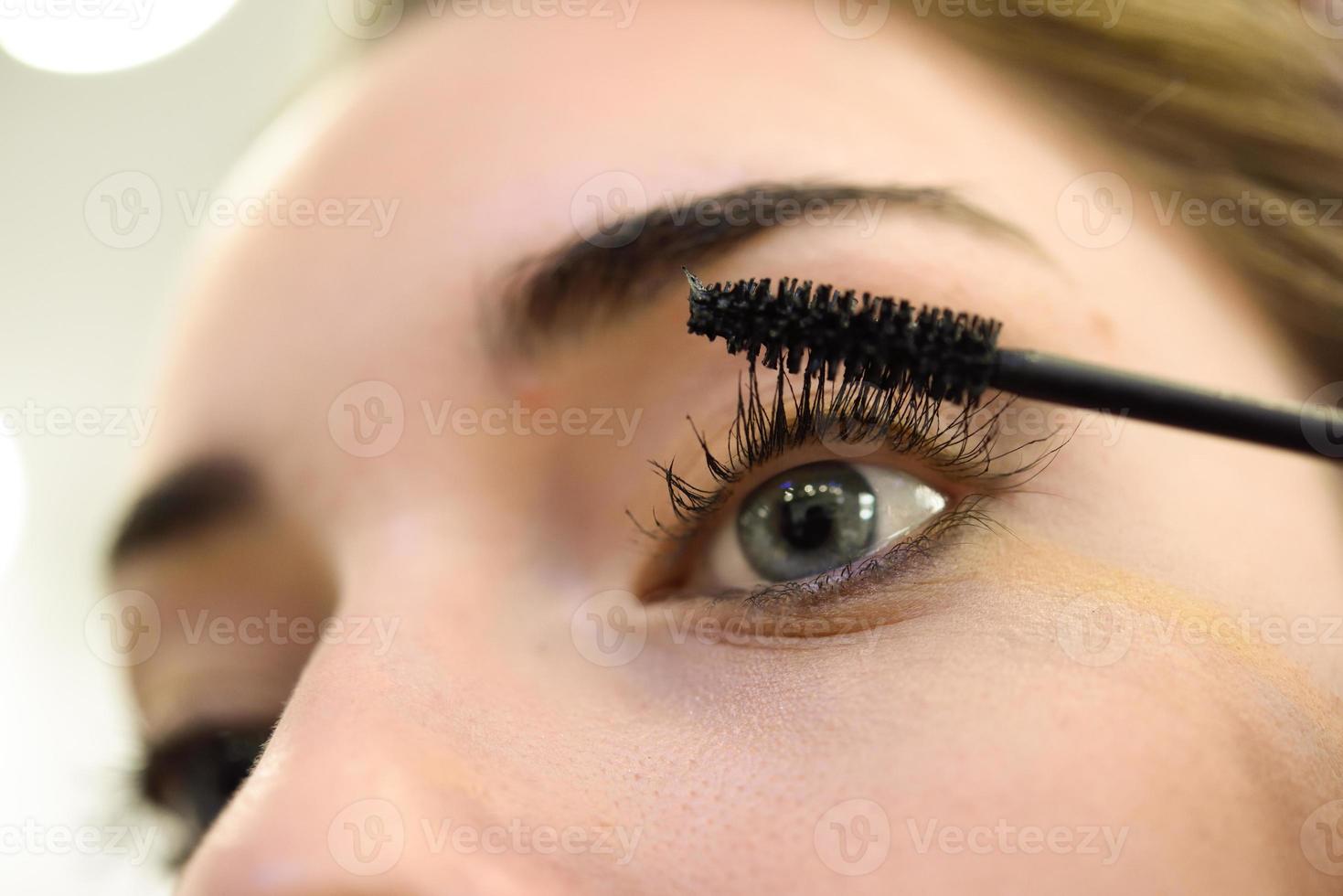 Make-up. Applying Mascara. Long Eyelashes and blue eyes photo