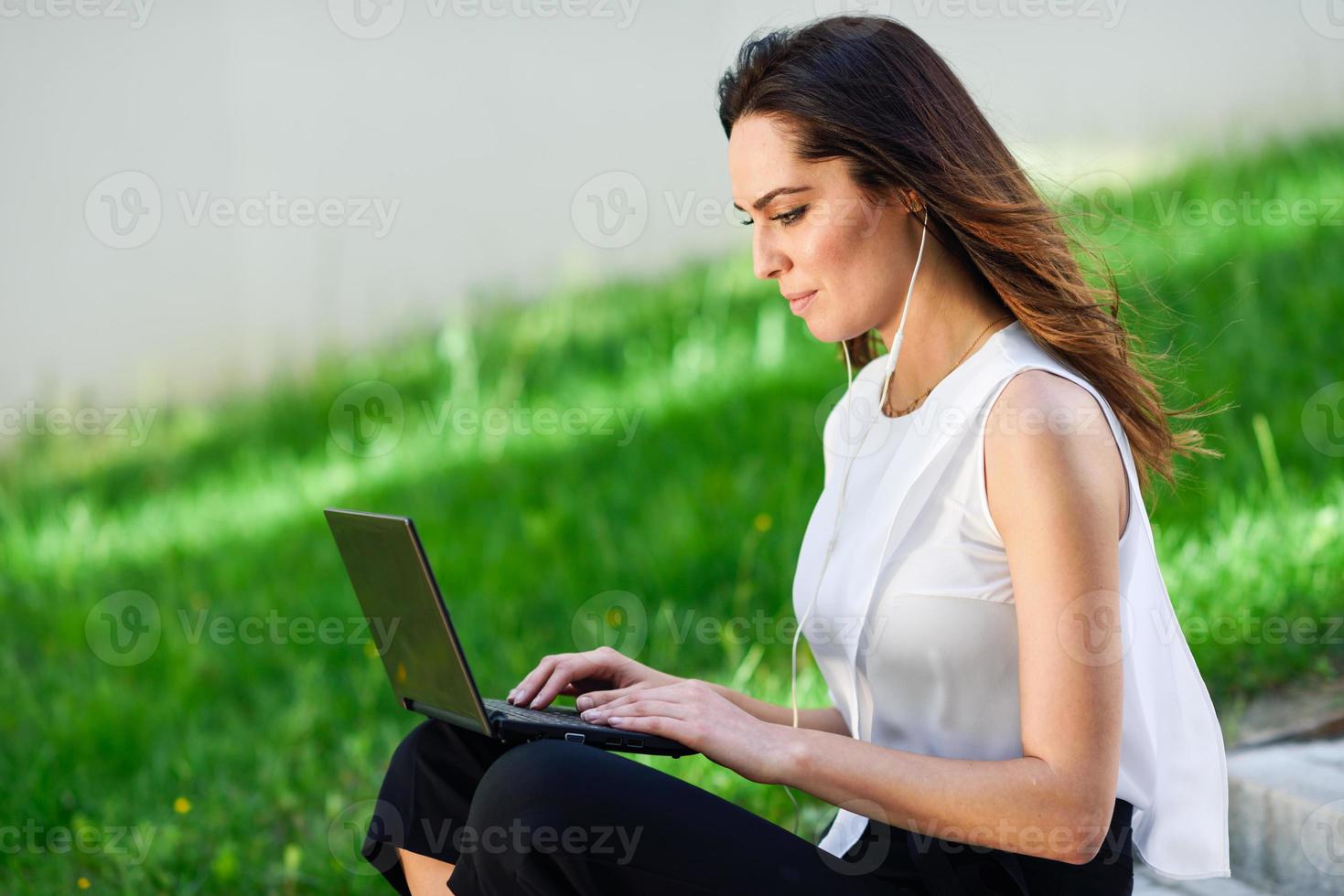 mujer joven que trabaja con su computadora portátil sentada en el suelo. foto