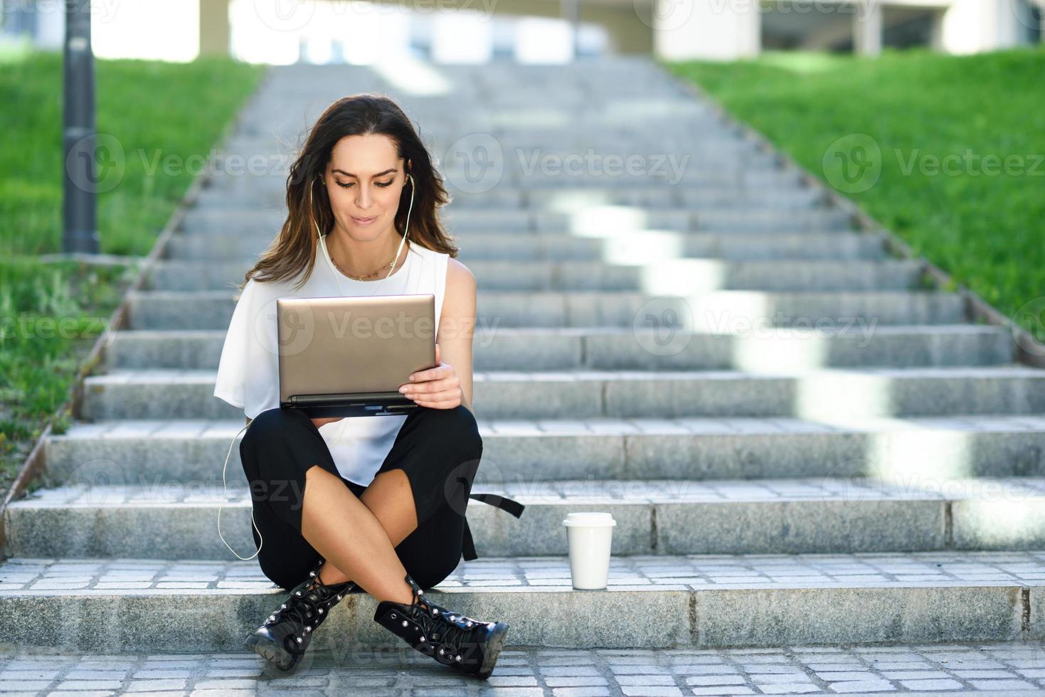 mujer joven que trabaja con su computadora portátil sentada en el suelo. foto