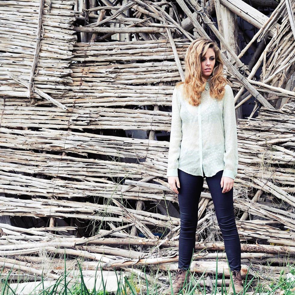 hermosa mujer rubia de pie junto a una antigua muralla foto