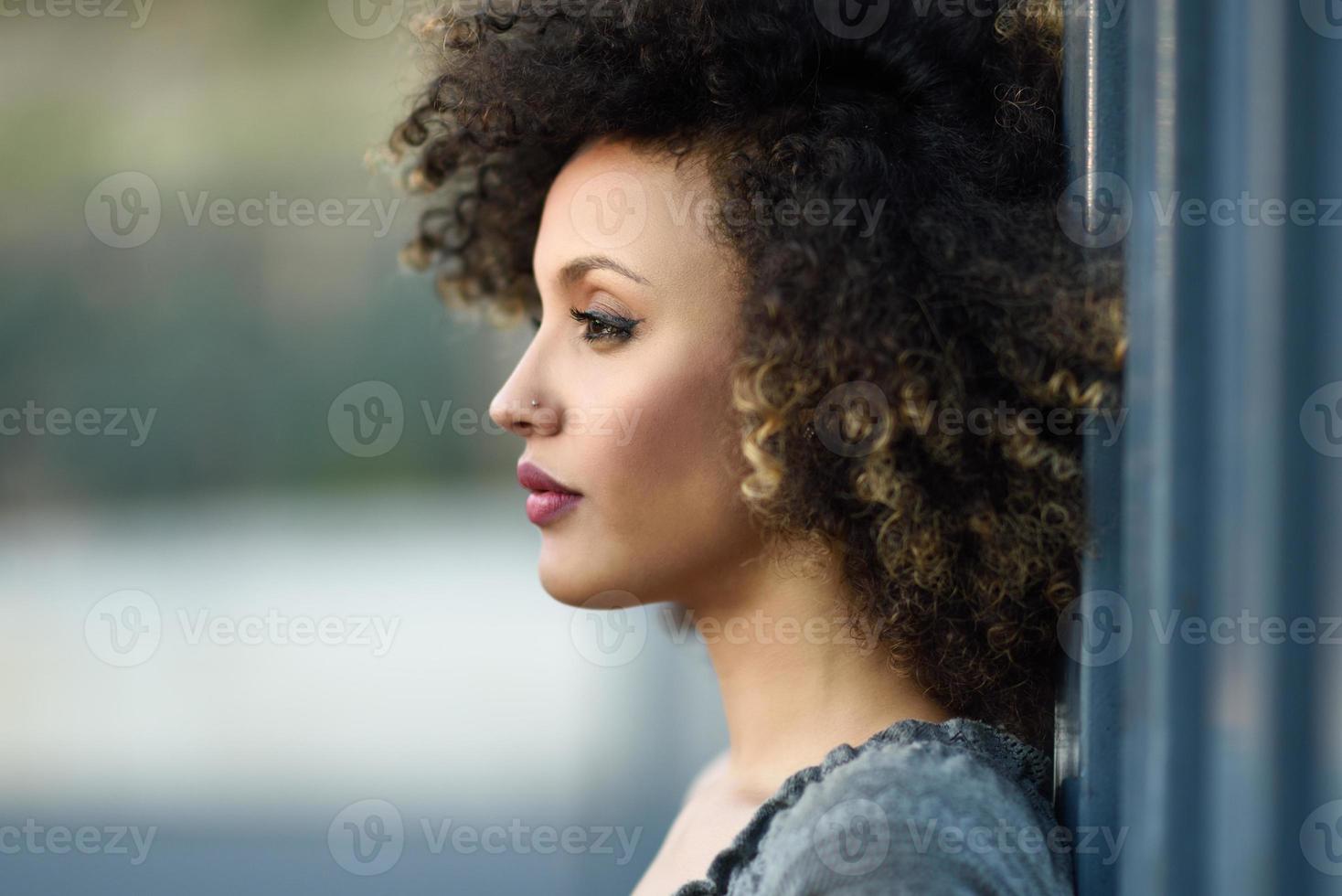 Young black woman with afro hairstyle smiling in urban background photo