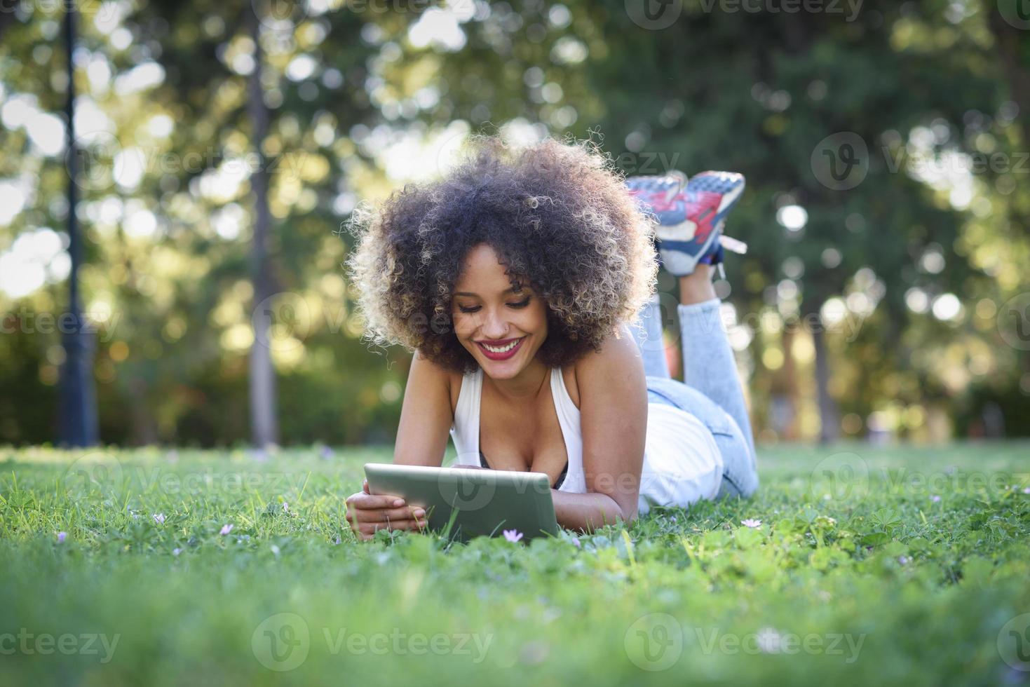 Mixed woman with afro hairstyle looking at her tablet computer photo