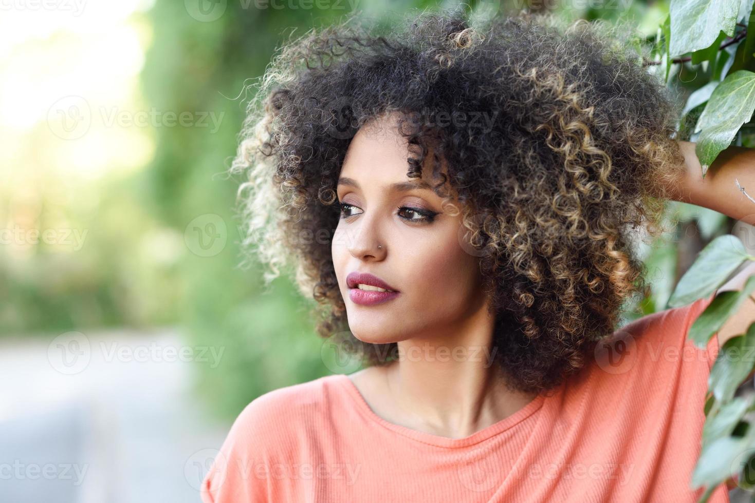 Black woman with afro hairstyle standing in an urban park photo